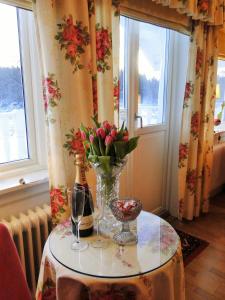 a table with a vase of flowers and wine glasses at Hotell Torpa Pensionat - Sweden Hotels in Södertälje