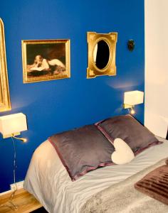 1 dormitorio con una pared azul, 1 cama y 2 lámparas en Le Moment Bleu, en Estrasburgo
