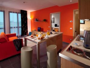 eine Küche mit orangefarbenen Wänden und ein Wohnzimmer in der Unterkunft Matrix Hotel & Residence in Vigonza