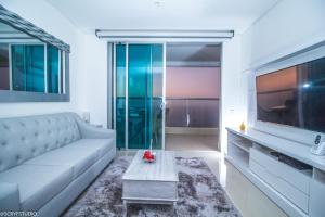 ein Wohnzimmer mit einem Sofa und einem TV in der Unterkunft Precioso apto de 1 habitación con vista extraordinaria en Bocagrande in Cartagena de Indias