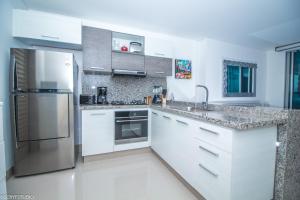 eine Küche mit weißen Schränken und einem Kühlschrank aus Edelstahl in der Unterkunft Precioso apto de 1 habitación con vista extraordinaria en Bocagrande in Cartagena de Indias
