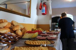 a person standing in front of a buffet of food at Beira Mar Hostel & Suítes in Abraão