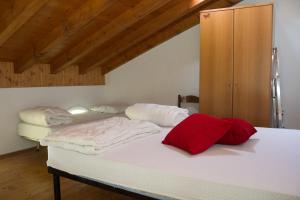 a bedroom with two beds with white sheets and red pillows at Casa Ornella in Ponte Caffaro