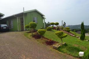 una casa verde con árboles y arbustos en un patio en Mkhumbane Backpackers en Durban