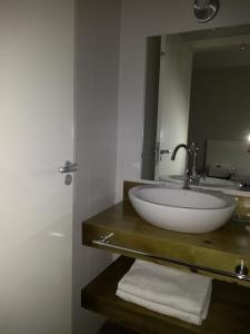 a bathroom with a sink with a mirror and towels at Piavi Residencial in São Francisco de Paula