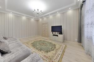 a living room with a couch and a tv at Apartment Lux 177 A in Astana