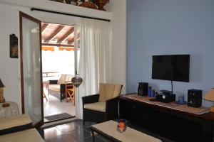 een woonkamer met een televisie en een woonkamer met een bank bij Acrogiali Sunshine in Siviri
