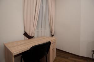 uma secretária de madeira com uma cadeira ao lado de uma janela em Wonderful flat on city center (Mukachivska 4/11) em Uzhhorod