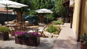 un patio con sillas y mesas con sombrillas y flores en Guesthouse Pintadera, en Santa Maria la Palma