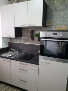a kitchen with white cabinets and a microwave and a sink at Studio Koper in Koper