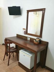 a wooden desk with a mirror and a chair at Casa do Manequinho Hotel e Restaurante in Piraí