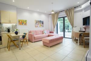 a living room with a pink couch and a kitchen at Porto Rafti view by Akroploro in Porto Rafti