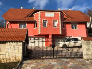 una casa naranja con una puerta y una valla en Kedvenc Vendégház, en Miskolctapolca