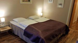 a bed in a room with two lamps on the wall at Bardu Hotell in Sætermoen