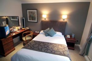 a hotel room with a large bed and a desk at Wainstones Hotel in Stokesley