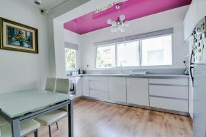 a kitchen with white cabinets and a purple ceiling at Carmel Boutique Apartments in Haifa