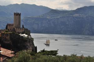 a boat in a large body of water with a castle at Hotel Augusta in Malcesine