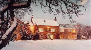 a house covered in snow in a yard at Wainstones Hotel in Stokesley
