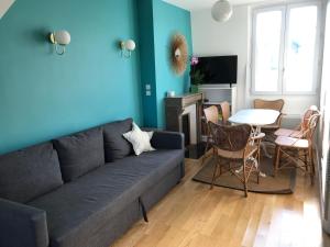 ein blaues Wohnzimmer mit einem Sofa und einem Tisch in der Unterkunft Deauville Triangle d OR in Deauville