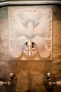 a sculpture of a lion with a mouth on a wall at Il Pievano B&B in Campiglia Marittima