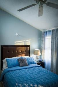 1 dormitorio azul con 1 cama y ventilador de techo en Country Club Comfort, en Portmore