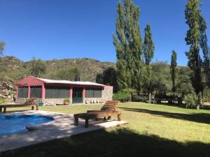 uma casa com piscina e um banco no quintal em Finca La Media Luna em San Agustín de Valle Fértil