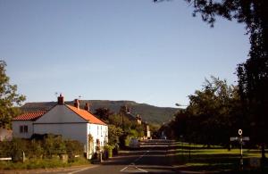 a street with a white house and a mountain at Wainstones Hotel in Stokesley