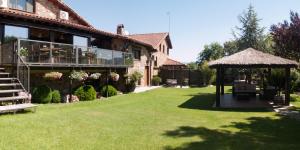 una casa con un patio de césped con cenador en Saika Rural, en Manjirón