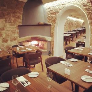 a restaurant with wooden tables and chairs and a fireplace at The Bunch Of Grapes Inn in Pissouri