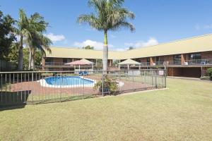 a fence in front of a building with a pool at Whiteoaks Motel & Lodges in Toowoomba