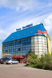 a large blue building with cars parked in a parking lot at Galitsiya Hotel in Lviv