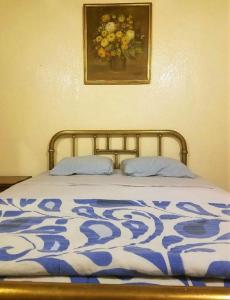 Una cama con una manta azul y blanca y una pintura en C huespedes Sn Angel Home - confirme reservacion al telefono siempre -, en Ciudad de México