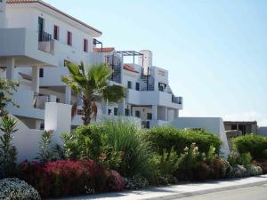 a white apartment building with a palm tree and plants at Cadiz Golf in Sanlúcar de Barrameda