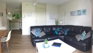 een woonkamer met een zwarte leren bank en een tafel bij Aquarius Batehaven in Batemans Bay