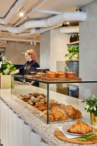 a woman standing behind a bakery counter with pastries at Tyrian Albert Park Lake in Melbourne