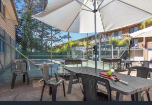 a table and chairs with an umbrella on a patio at Aquarius Batehaven in Batemans Bay