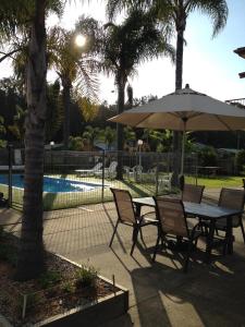 a table and chairs with an umbrella next to a pool at Aquarius Batehaven in Batemans Bay