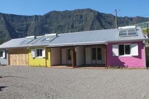 a colorful house with mountains in the background at les cases prés du lac in Cilaos