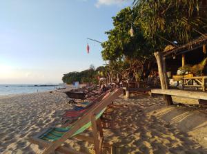 een strand met een rij strandstoelen erop bij Relax Beach House in Koh Lanta