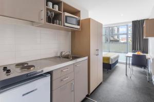 a kitchen with a sink and a stove top oven at Tetra Serviced Apartments by Castle in Auckland