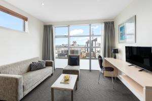 a living room with a couch and a desk with a tv at Tetra Serviced Apartments by Castle in Auckland