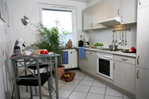 Ferienwohnung Zum alten Zollhaus في بيرغن: مطبخ فيه دواليب بيضاء وطاولة فيه