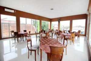uma sala de jantar com mesas, cadeiras e janelas em RedDoorz Plus @ Timoho em Yogyakarta