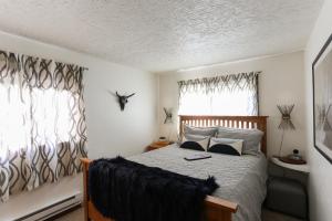 a bedroom with a bed and two windows at POW HAUS: Modern Beaver Creek 2BR w/ Ski Access in Avon