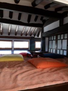 a bed with two pillows in a room with windows at Hundred Years Hanok in Mokpo