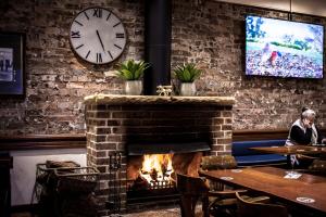 a fireplace in a restaurant with a clock on the wall at Blue Gum Hotel in Hornsby