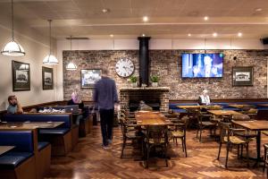 a man walking through a restaurant with a clock on the wall at Blue Gum Hotel in Hornsby
