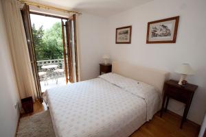 a bedroom with a white bed and a balcony at Apartments Villa Castello in Crikvenica