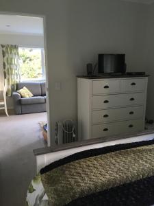uma sala de estar com uma cómoda e um espelho em Incline Cottage em Upper Hutt