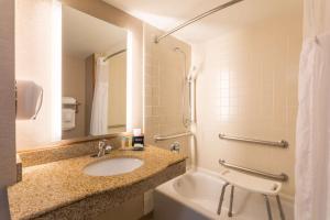 a bathroom with a sink, mirror, and bathtub at Wingate by Wyndham - Universal Studios and Convention Center in Orlando